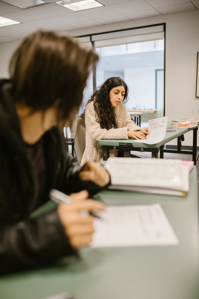 A student showing her work to another student for them to copy.