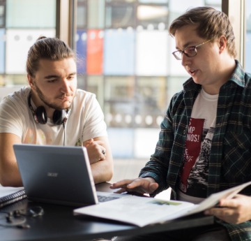 two male students sat at table with laptop