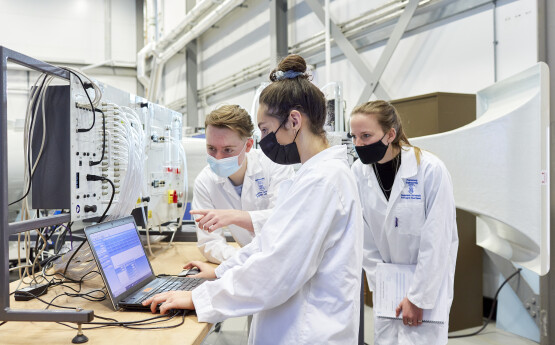 Engineering students wearing white overalls, working on a project together