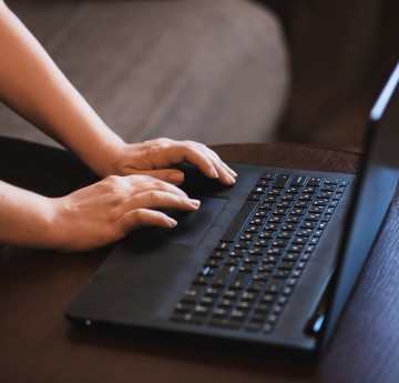 Two hands typing on a black laptop keyboard