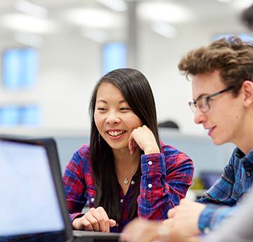 A male and female student working at a PC in PC lab on campus