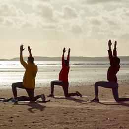 Pobl yn gwneud yoga ar draeth Abertawe