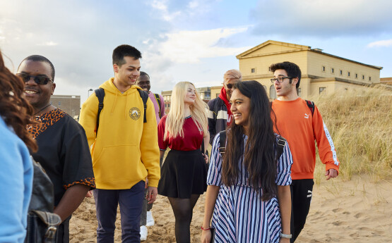 Students calling on beach by Bay Campus. 