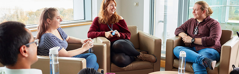 Students in ILS2 Hub chatting on the sofas.