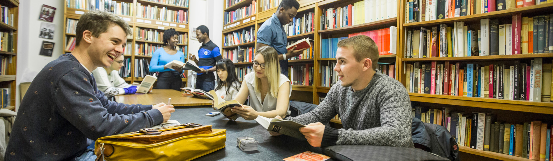 Students in library talking and looking at books