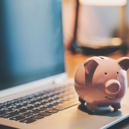 Piggy bank next to open laptop