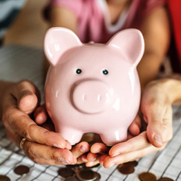 Two hands cradling a pink piggy bank