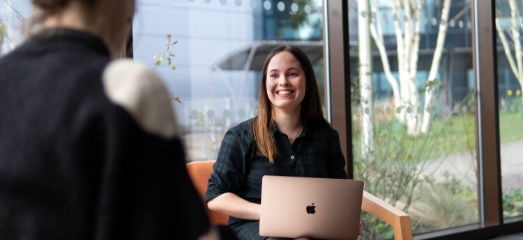 student simling in front of laptop