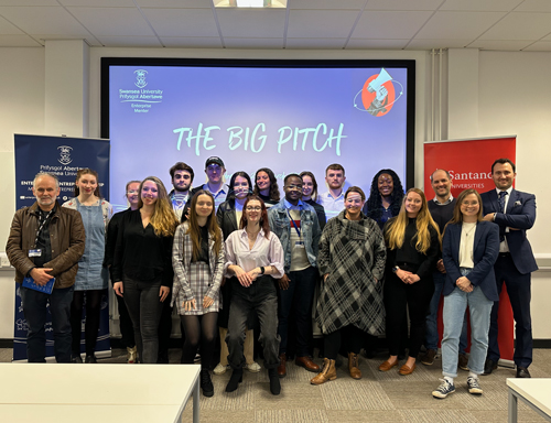 group of students and staff standing in front of a screen 