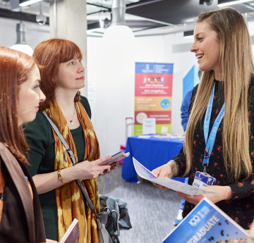 A member of staff assists two students with a form