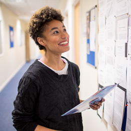 Smiling female student looking at a noticeboard 