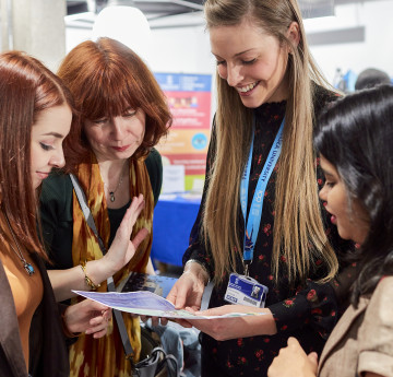 4 women looking at a document on an open day