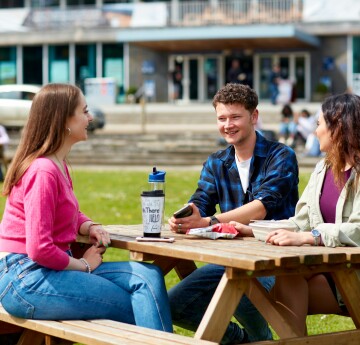 Group of students sitting outside on Fulton lawn chatting 