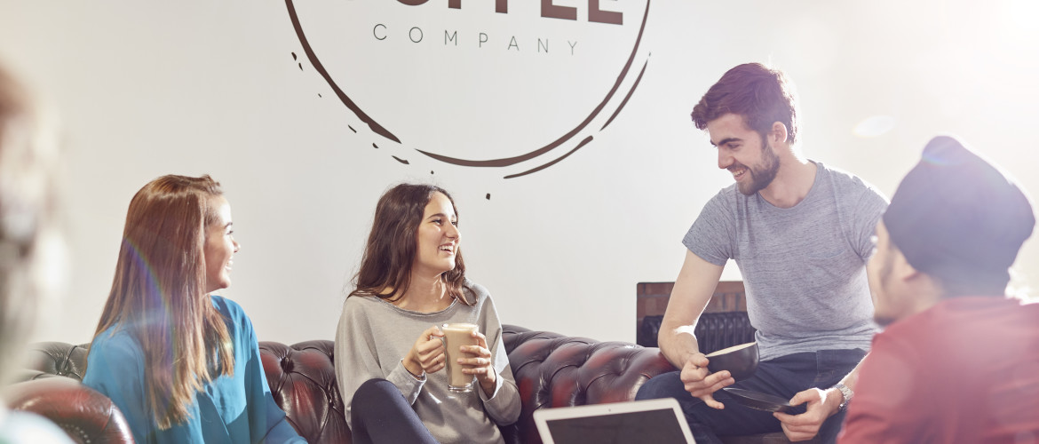 four students sat around a table drinking coffee in Fulton Coffee House