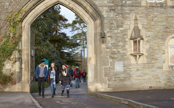 Three students walking through the gatehouse at Singleton Park